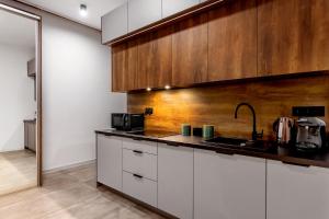 a kitchen with white cabinets and a wooden wall at Warowna 2 Premium Spa Jacuzzi & Sauna in Pszczyna