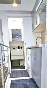 La cuisine blanche est équipée d'un évier et d'un réfrigérateur. dans l'établissement Villa Hélène, à Créteil