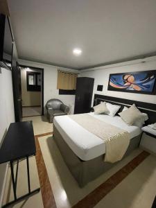Schlafzimmer mit einem Kingsize-Bett und einem Stuhl in der Unterkunft Hotel Plaza Norte Cali in Cali