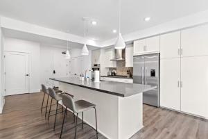 a kitchen with white cabinets and a counter with stools at Luxurious 2-Bedroom 2-Bath Unit with Marina Views in Los Angeles
