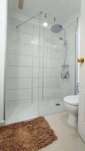 een badkamer met een glazen douche, een toilet en een tapijt bij Residential Golf Park - Casa Prezi in San Miguel de Abona