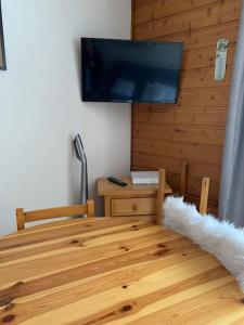 Habitación con mesa de madera y TV de pantalla plana. en Appartement au pied des pistes, en Châtel