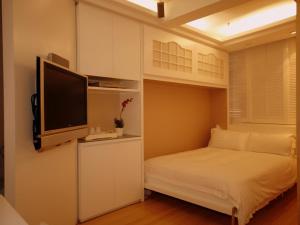 una piccola camera con letto e TV a schermo piatto di Mingle At The Eden a Hong Kong