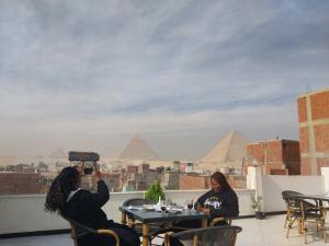 twee vrouwen aan een tafel die een foto nemen van de piramiden bij Eagles Pyramids View in Caïro
