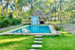 a small swimming pool in a yard with a hut at Villa Cielo, Casa de playa in Jacó