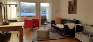 a living room with a black leather couch and red chairs at Ferienwohnung Belchenblick in Staufen im Breisgau
