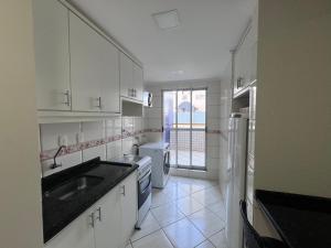 a white kitchen with a sink and a refrigerator at APTO no Centro, COMPLETO, UNIPAR e SHOPPING JL in Cascavel