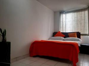 1 dormitorio con 1 cama con manta roja y ventana en alojamiento cerca centro histórico Popayán., en Popayán