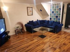 a living room with a blue couch and a television at Home Away in a Close in Thamesmead