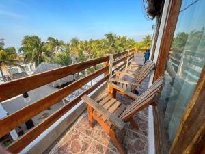 Dos bancos en un balcón con vistas al océano en Casa Tropicana en El Cuyo
