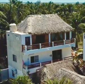una casa con techo de paja y palmeras en Casa Tropicana en El Cuyo