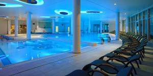a pool in a hotel with chairs around it at Grand Lubicz Uzdrowisko Ustka in Ustka