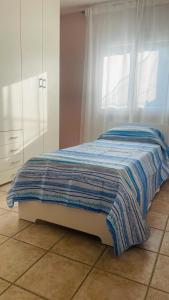 a bed with a blue and white blanket on the floor at Appartamento Polpenazze in Polpenazze del Garda