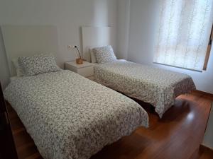1 dormitorio con 2 camas y ventana en Playa del prado, en Ribeira