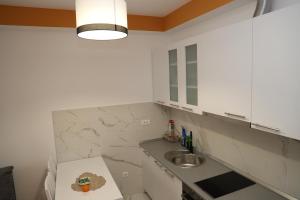 a white kitchen with a sink and a counter at Apartman Solunska 18 Banja Luka in Banja Luka +5 photos