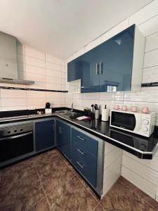 eine Küche mit blauen Schränken und einer Mikrowelle in der Unterkunft Avenida 52 B in Los Llanos de Aridane