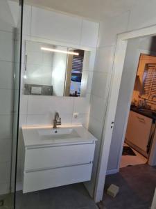 a white bathroom with a sink and a mirror at Heerlijk halfvrijstaande woning in Hierden
