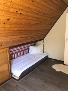 a small bed in a room with a wooden ceiling at Heerlijk halfvrijstaande woning in Hierden