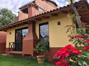 a house with windows and red flowers in the yard at Brisas de Sol in Pátzcuaro