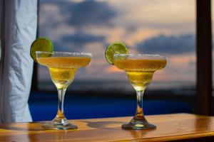 dos cócteles en una mesa de madera con una cuña de limón en Casa Playa James, en Los Arrayanes
