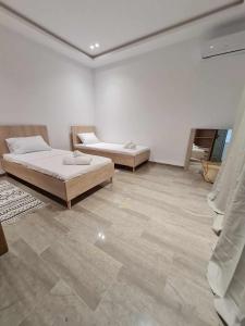 2 Betten in einem weißen Zimmer mit Fliesenboden in der Unterkunft Raya in Midoun