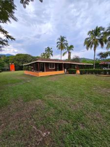 a house with palm trees and a grass yard at Finca la Querendona in Santa Fe de Antioquia