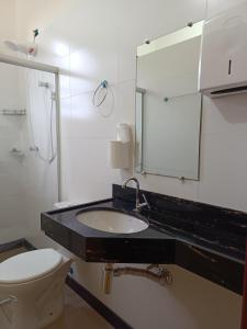 een badkamer met een wastafel, een toilet en een spiegel bij É Hostel - Guesthouse in Ouro Preto