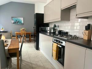a kitchen with white cabinets and a table and a dining room at Luxury Victorian House Sleeps 6 - 11 Guests JLR, Trades, Relocations & Hs2 Welcome Wheelchair Accessible Home FREE Faster WIFI & PARKING in Coventry