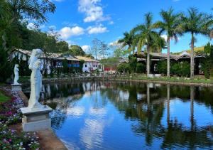 a statue next to a pond with palm trees at Pousada Villa Paolucci in Tiradentes
