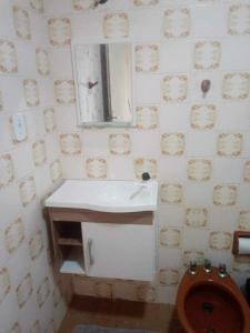 a bathroom with a toilet and a sink and a mirror at Apartamento Saquarema Centro in Saquarema