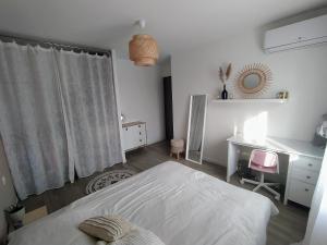 1 dormitorio con cama blanca, escritorio y ventana en Logement 3 chambres/terrasse à Teyran, en Teyran