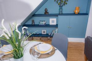 un comedor con una mesa blanca y una pared azul en Midsummer Cottage Cambridge en Chesterton