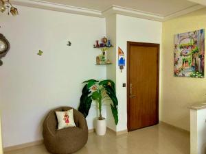 een woonkamer met een stoel en een plant bij Appartement beau et familial connecté in Tanger