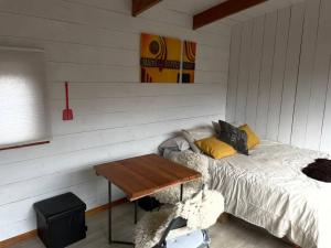 Habitación con cama y mesa de madera. en Tiny Harry Malalcahuello, en Curacautín