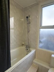 a bathroom with a bath tub and a window at Beautiful Studio Apartment No4 Forest Road in London