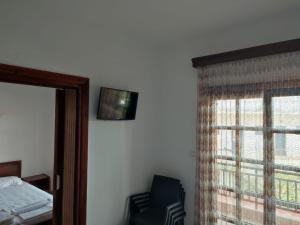 ein Schlafzimmer mit einem Bett und einem Stuhl neben einem Fenster in der Unterkunft Ξενώνας Φωτεινη in Ouranoupoli