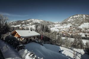 a house covered in snow with mountains in the background at Nards furnished chalet in Praz-sur-Arly