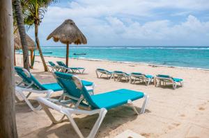 a group of chairs and an umbrella on a beach at Beachfront Hammock Heaven in Akumal