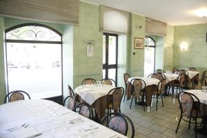 un restaurante con mesas y sillas blancas y ventanas en Hotel Narnia, en Narni