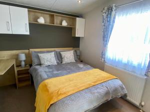 a bedroom with a bed with a yellow blanket and a window at Hot tub. Countryside. Coast. 5* Patrington Haven Leisure Park, East Yorkshire in Patrington