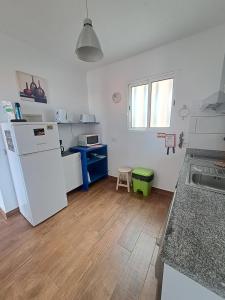 een keuken met een witte koelkast en een houten vloer bij Happy House Madeira in Funchal