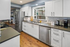 una cocina con armarios blancos y electrodomésticos de acero inoxidable en Cozy Cloverdale BY Betterstay en Seattle