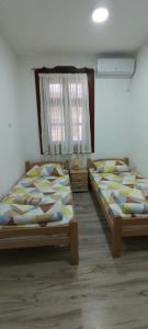 two twin beds in a room with a window at Aurora Apartment in Kikinda