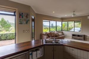a kitchen with a sink and a living room at TAIRUA SLICE OF PARADISE! in Tairua
