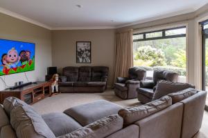 a living room with two couches and a flat screen tv at TAIRUA SLICE OF PARADISE! in Tairua
