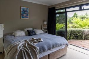 a bedroom with a bed with a blanket and a window at TAIRUA SLICE OF PARADISE! in Tairua