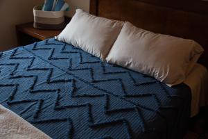 ein Bett mit einem weißen Kissen und einer blauen Decke in der Unterkunft Estancia 104 in La Paz