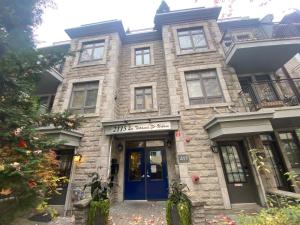 - un grand bâtiment en pierre avec une porte bleue dans l'établissement Apart Hotel Montreal by Les Terrasses Saint Urbain, à Montréal