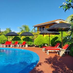 a pool with chairs and umbrellas next to a house at Hotel Jardín Garden de Granada Nicaragua in Granada