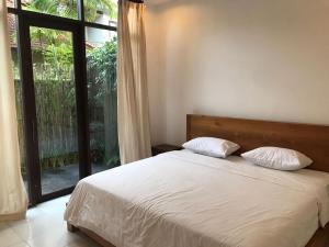 ein Bett mit zwei Kissen in einem Schlafzimmer mit einem Fenster in der Unterkunft De, dalam secret nature in Ubud